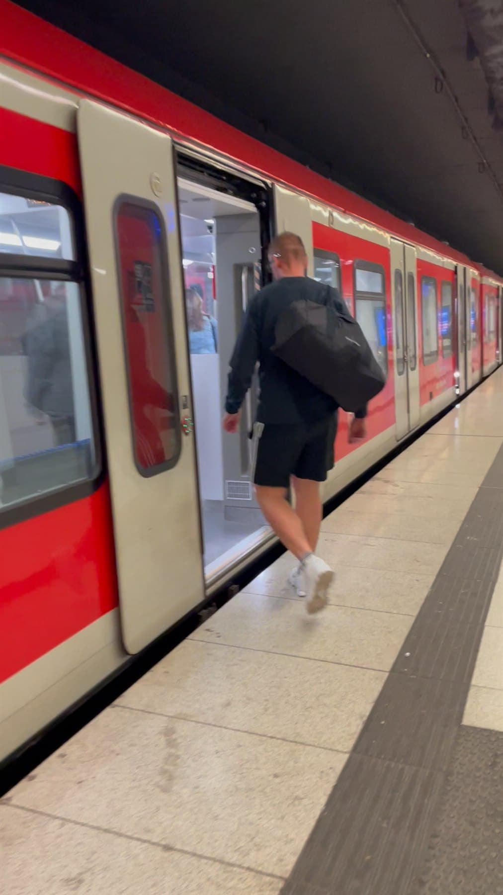 Passenger boarding a red Hamburg S-Bahn train back to Hamburg Hauptbahnhof
