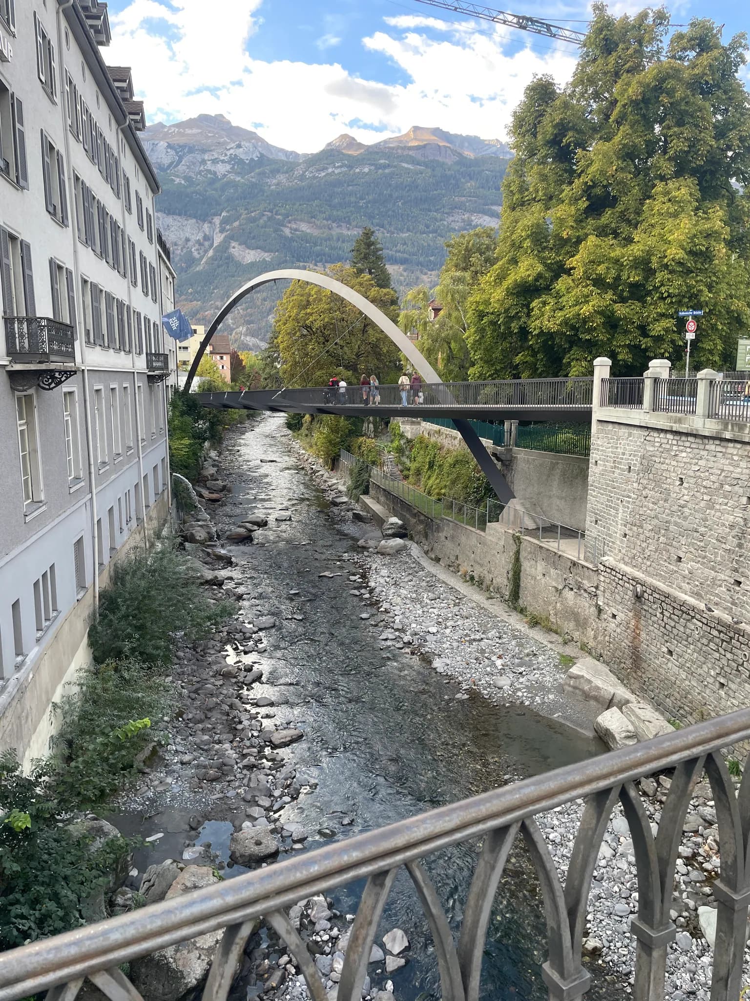 Plessur river and a pedestrian bridge in Chur with mountains behind the city