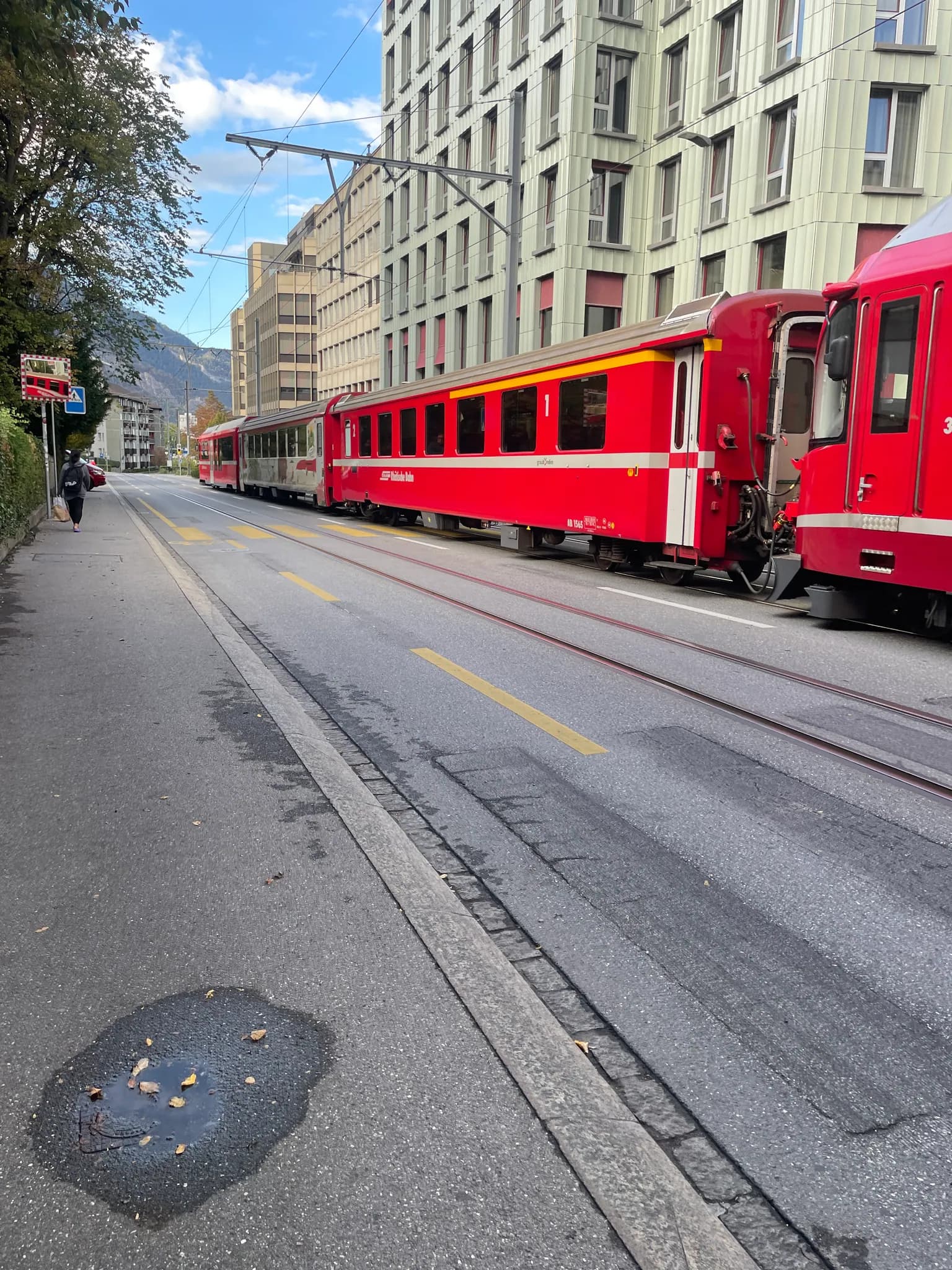 Red Rhätische Bahn train from the Chur–Arosa line running along a city street