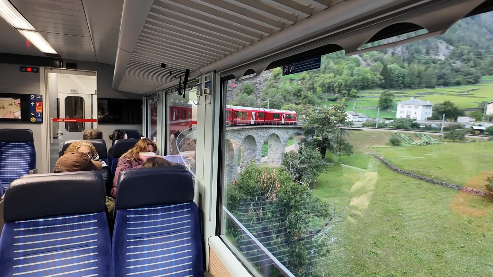 Red Rhätische Bahn train curving across the stone Brusio Circular Viaduct
