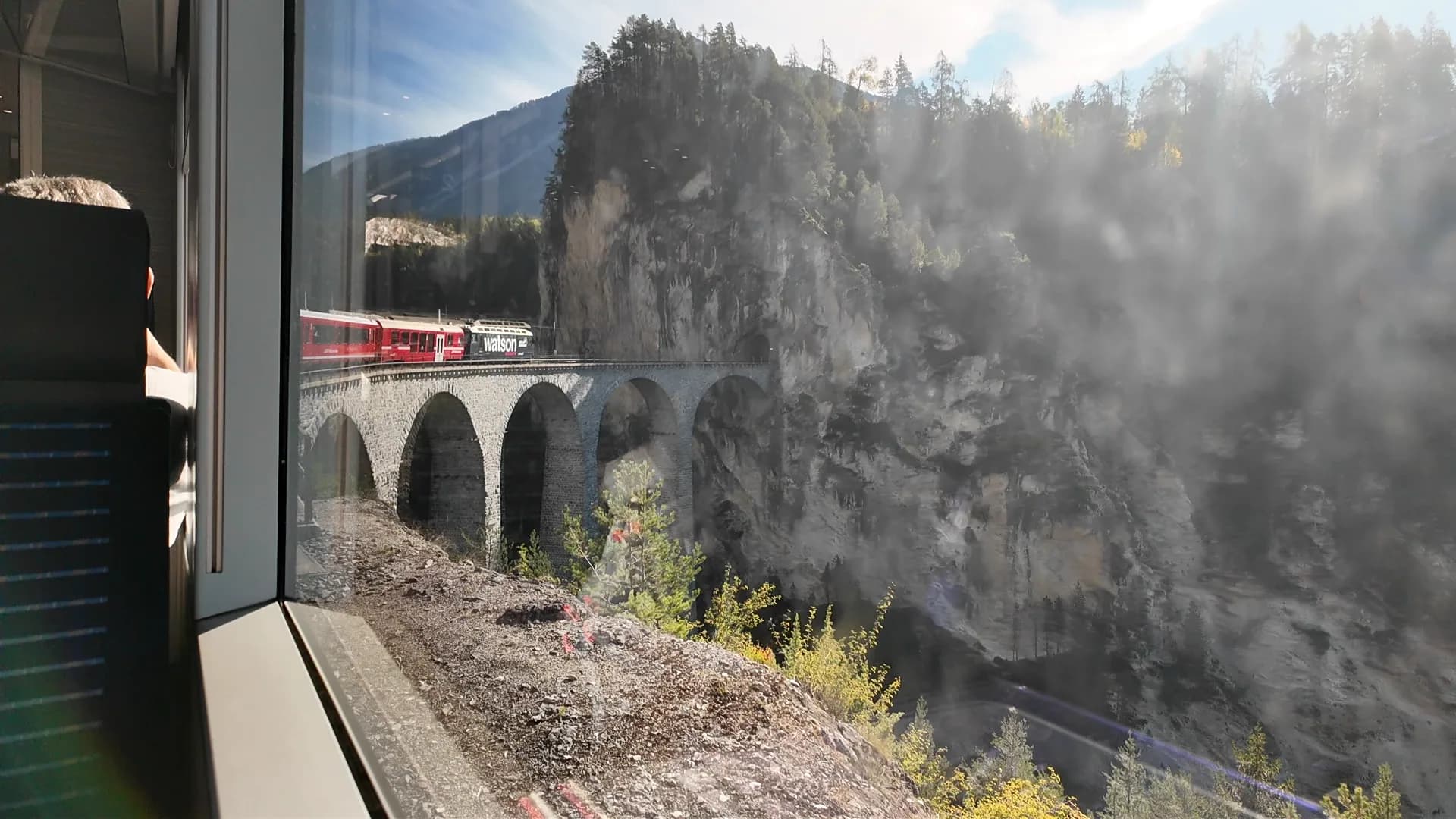 Regional train crossing the curved Landwasser Viaduct before entering its mountain tunnel