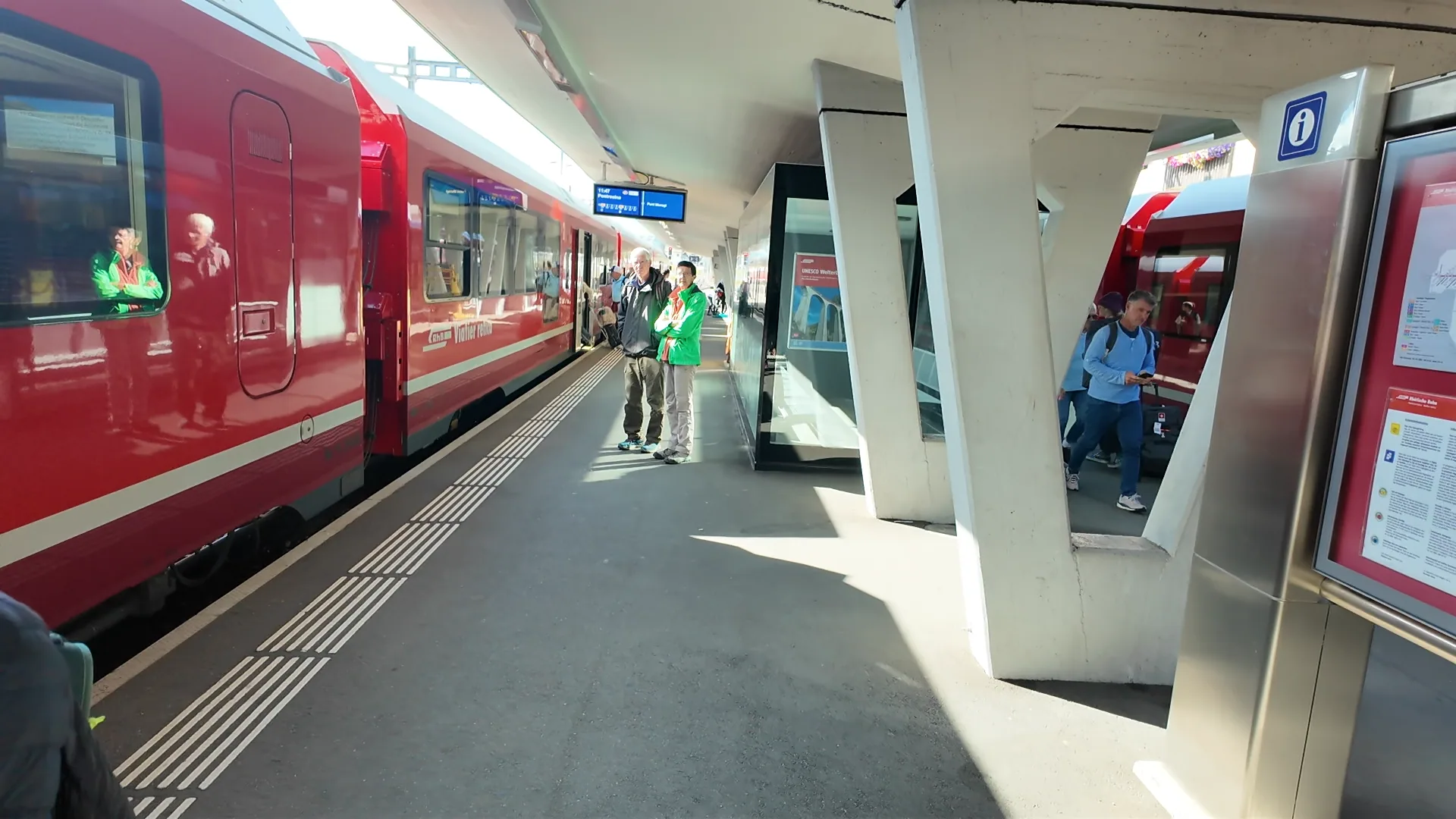 Platform at Samedan with a regional train and departure display showing 11:47 to Pontresina