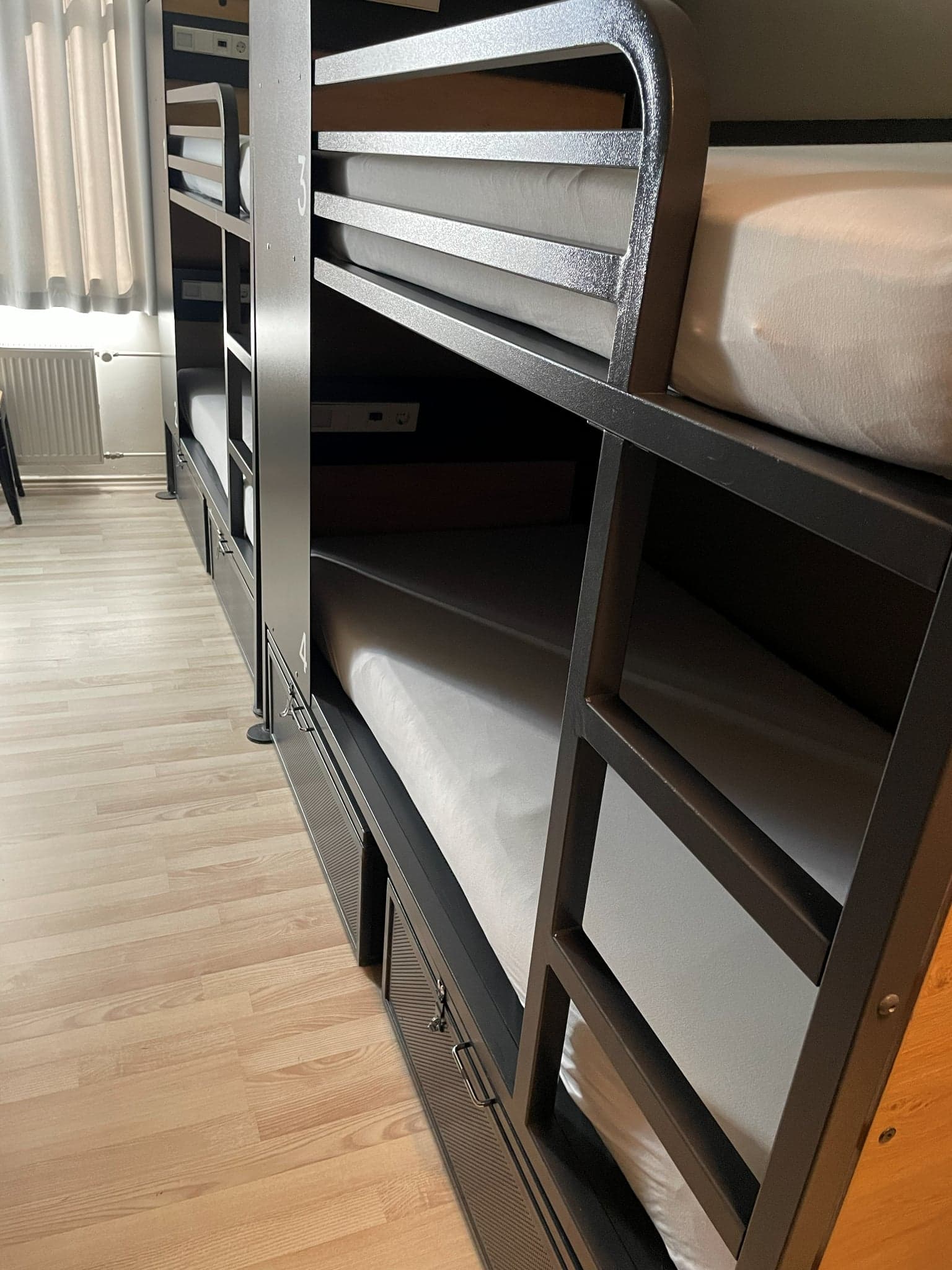 Four-person mixed dorm with black bunk beds at Generator Hostel Hamburg