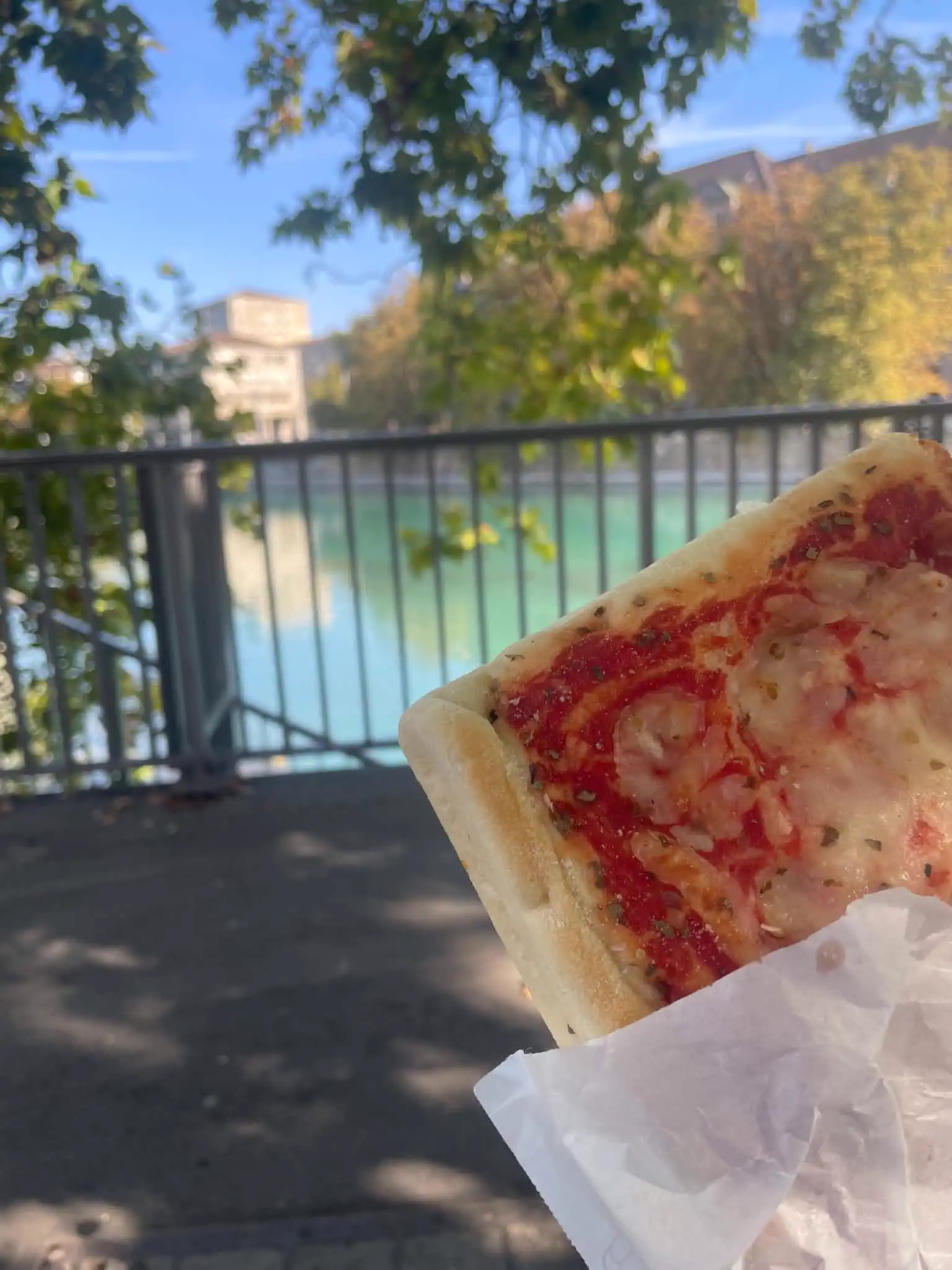 A Coop pizza slice eaten beside the turquoise Limmat river in Zürich